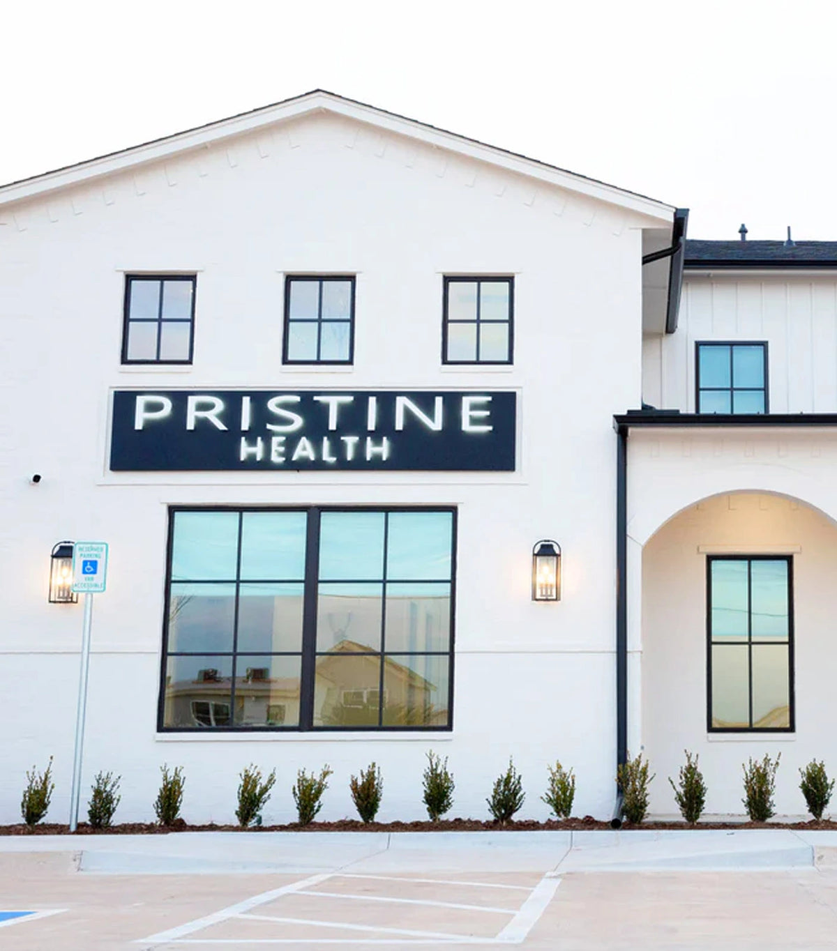 Pristine Health Sooner Road clinic exterior — white building with illuminated Pristine Health sign, modern windows, and parking in North Edmond, OK