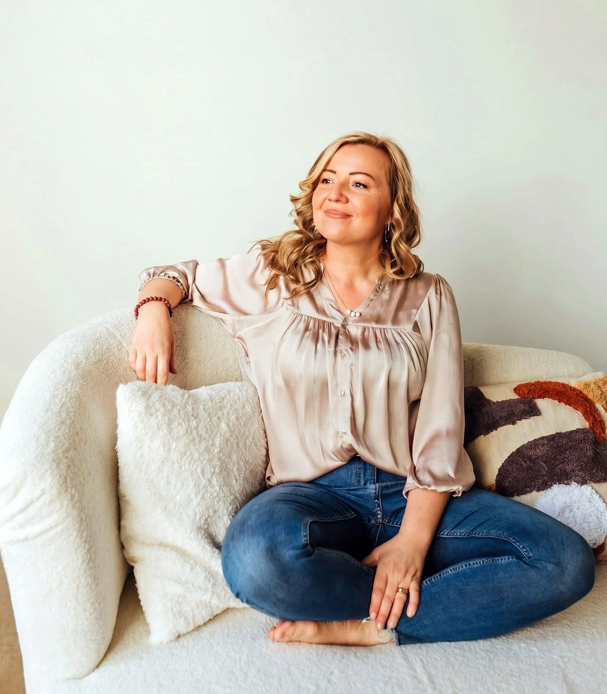 A smiling woman sitting comfortably on a cream sofa