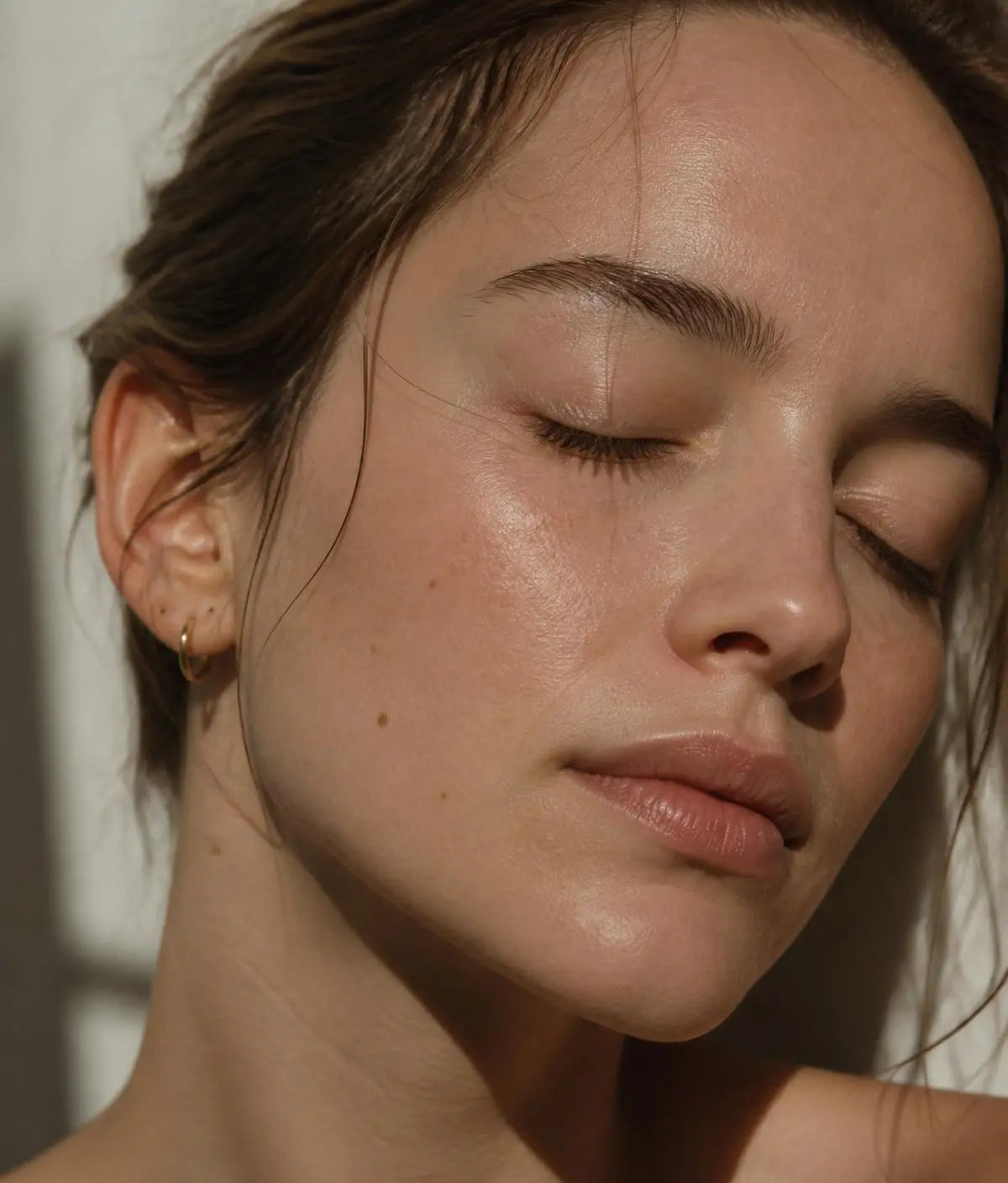 Woman with eyes closed and glowing skin in soft natural light